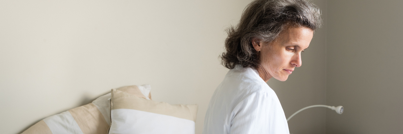 Was My 'Random' Panic Attack Related to COVID-19 or Something Else? middle-aged woman sitting on the edge of her bed looking down somberly