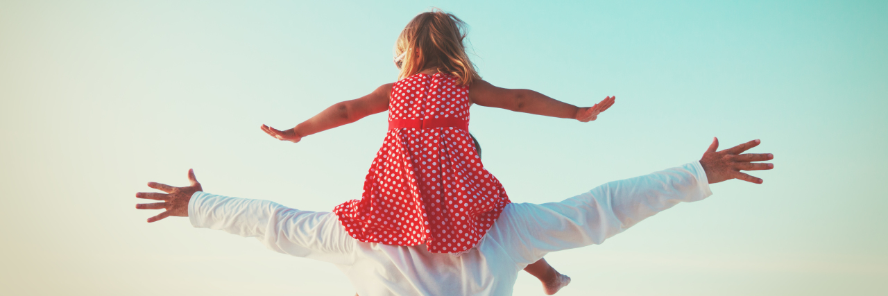 To My Small, Warrior Daughter 7 Months After Her Surgeries a little girl sitting on her dad's shoulder with their arms stretched out