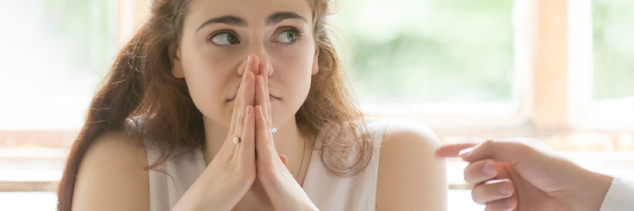 Personal Experience: Mental Illness Discrimination in the Workplace photo of young woman looking worried in work meeting with people pointing at her