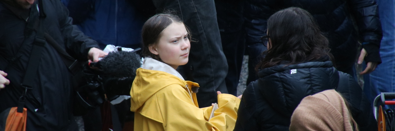 Greta Thunberg is surrounded by people at a protest