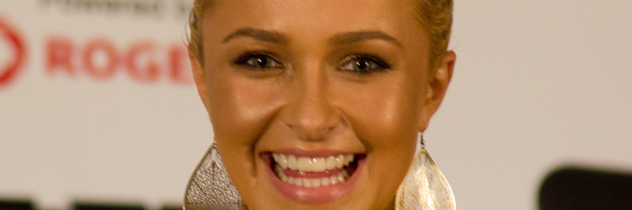 Hayden Panettiere smiles at an event in a yellow outfit
