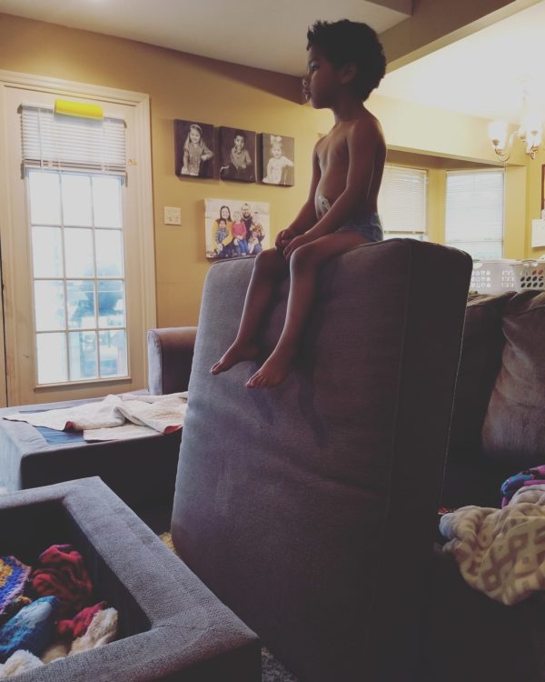 little boy sitting on top of couch cushion