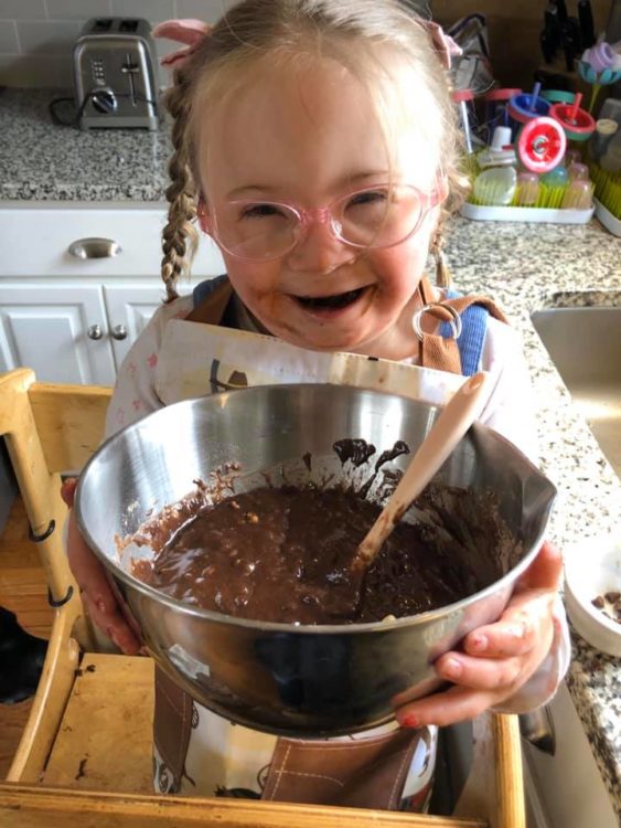 little girl with Down syndrome making a cake