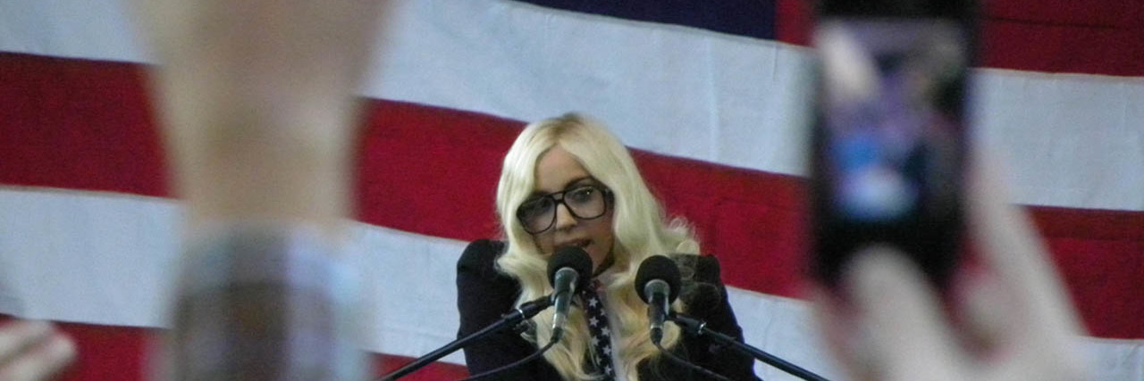 Lady Gaga makes a speech onstage while wearing a black ensemble