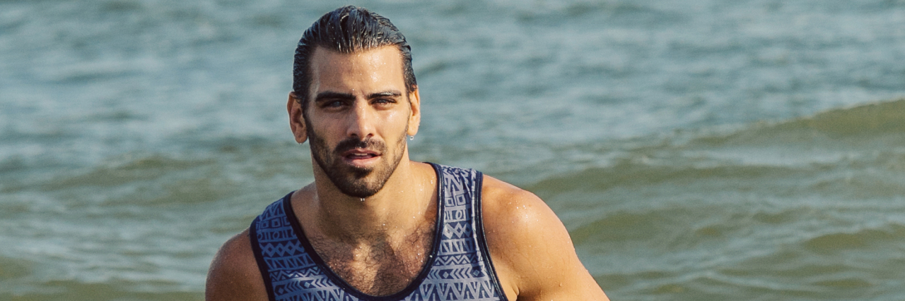 Nyle DiMarco models for the camera in the ocean at a beach