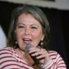 Roseanne Barr in a striped shirt speaks into a microphone