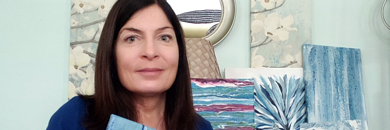 Tools to Help With Chronic Pain from Klippel-Feil Syndrome the author holding up her painting, smiling.