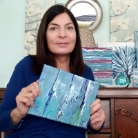 the author holding up her painting, smiling.
