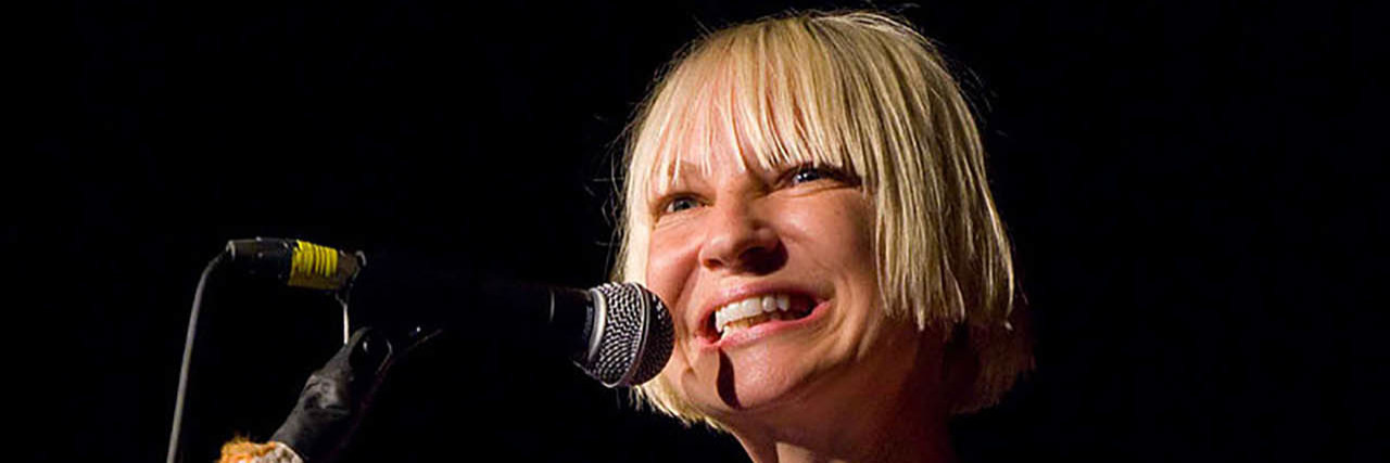 Sia singing onstage in a black dress