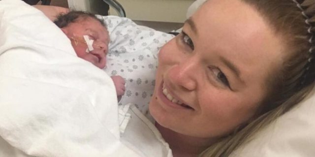 Maintaining Hope Amid My Baby's Cornelia de Lange Syndrome Diagnosis A mother is smiling at the camera while holding her newborn baby in the hospital after birth.