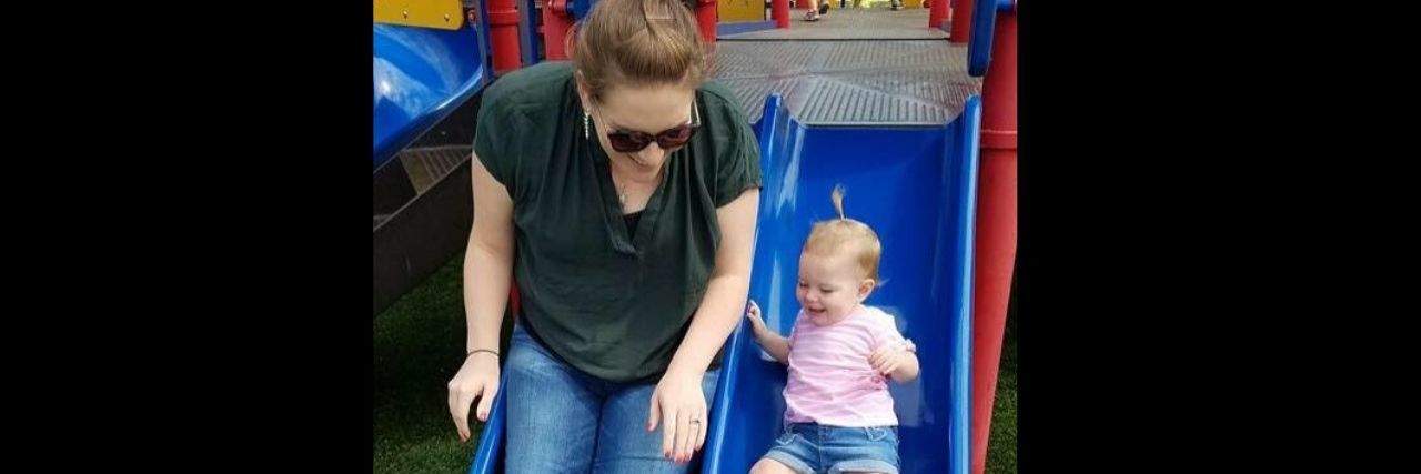 How Being a New Mom With Anxiety Taught Me to Love Myself A mom and her young daughter are going down a slide.