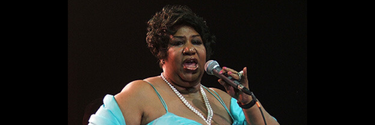 Aretha Franklin sings onstage while in a blue dress