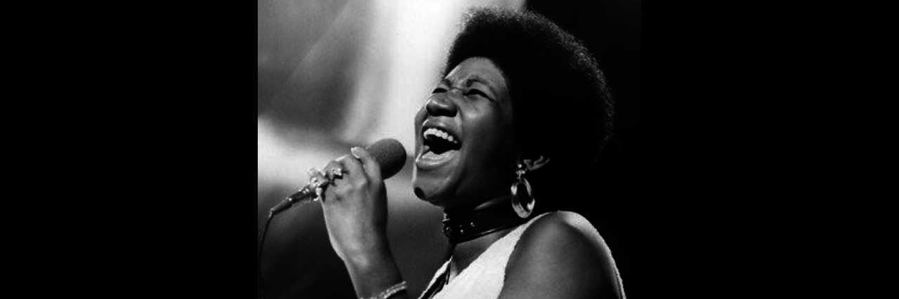A photo of a younger Aretha Franklin singing onstage