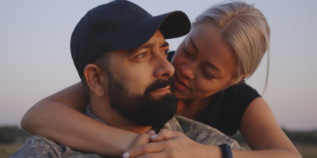 A woman with her arms around a man in a military uniform