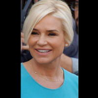 Yolanda Hadid in a blue outfit smiles at a red carpet event