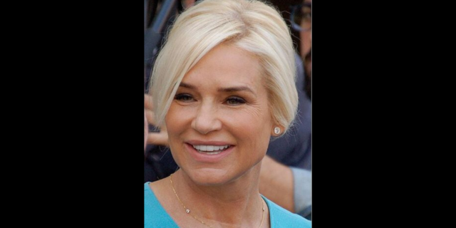 Yolanda Hadid in a blue outfit smiles at a red carpet event