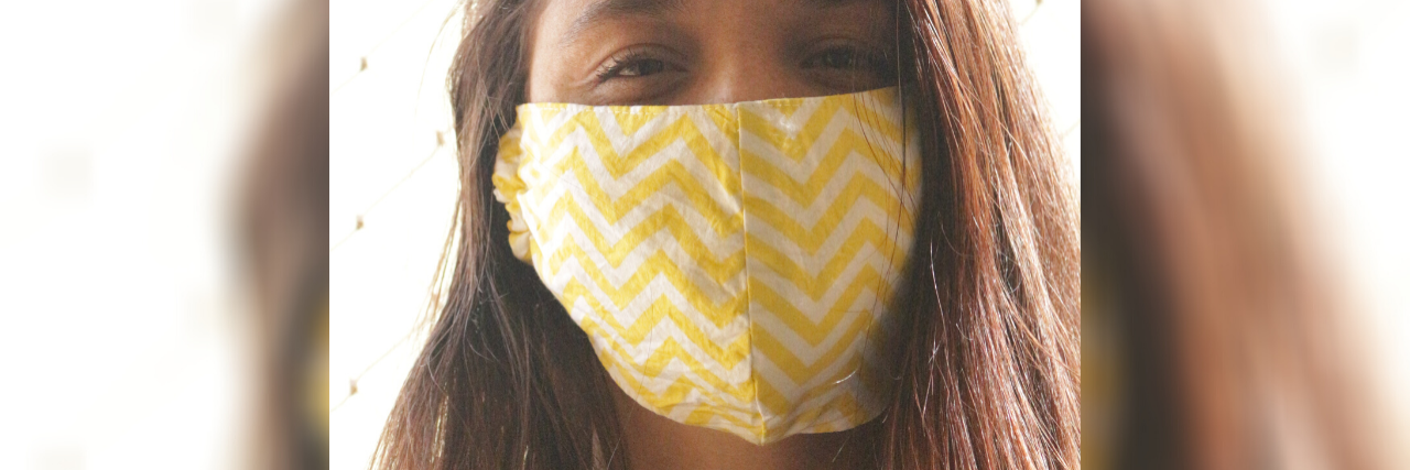 photo of woman wearing yellow face mask and smiling with her eyes, looking into camera