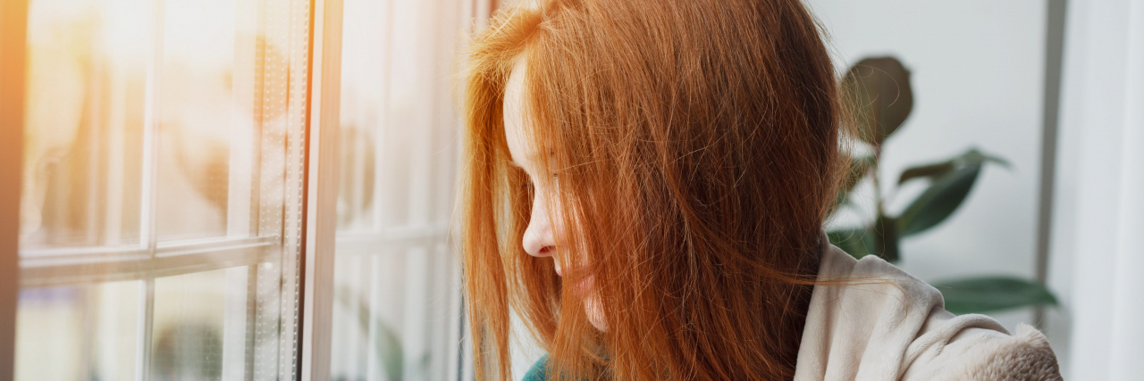 Woman with red hair looking out window