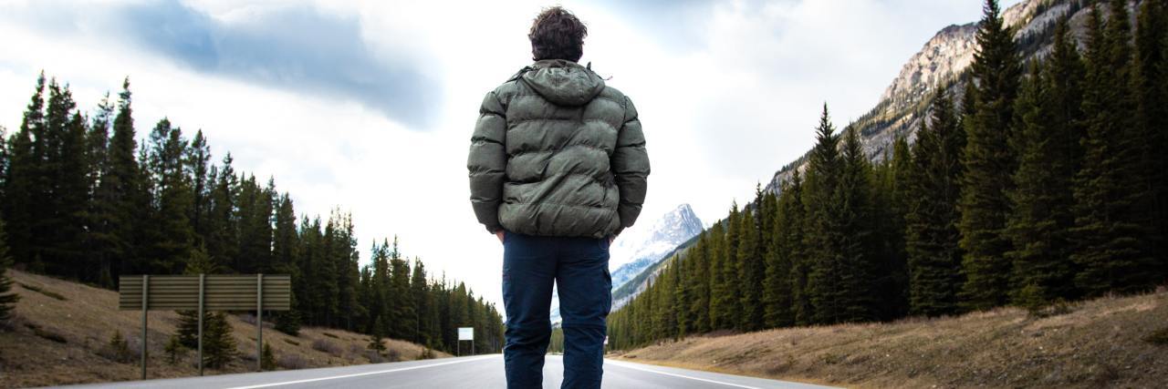 We Need to Support People With Facioscapulohumeral Muscular Dystrophy man in a winter jacket and jeans standing in the middle of a road with his back to the camera