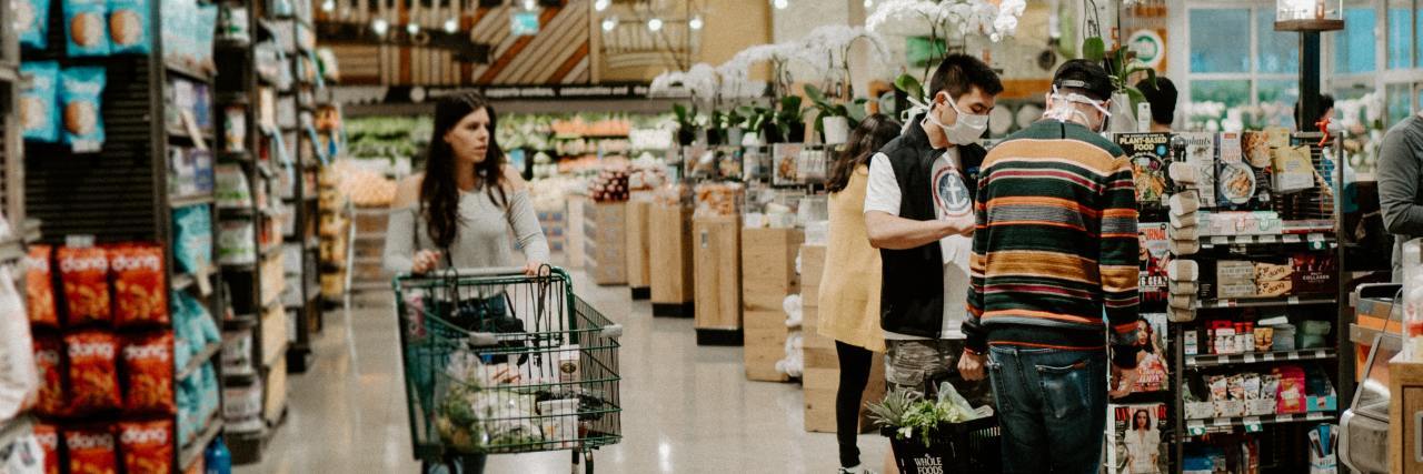 What to Know If You Feel Judged Buying Non-Essentials During COVID-19 photo of shoppers in convenience store with some wearing face masks