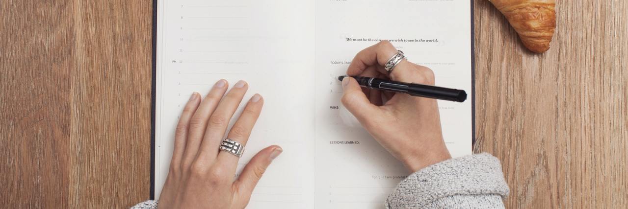 6 Helpful Reminders for My Bad Days With Depression woman writing notes down in a journal with a black cup of a coffee and croissant sitting on the table