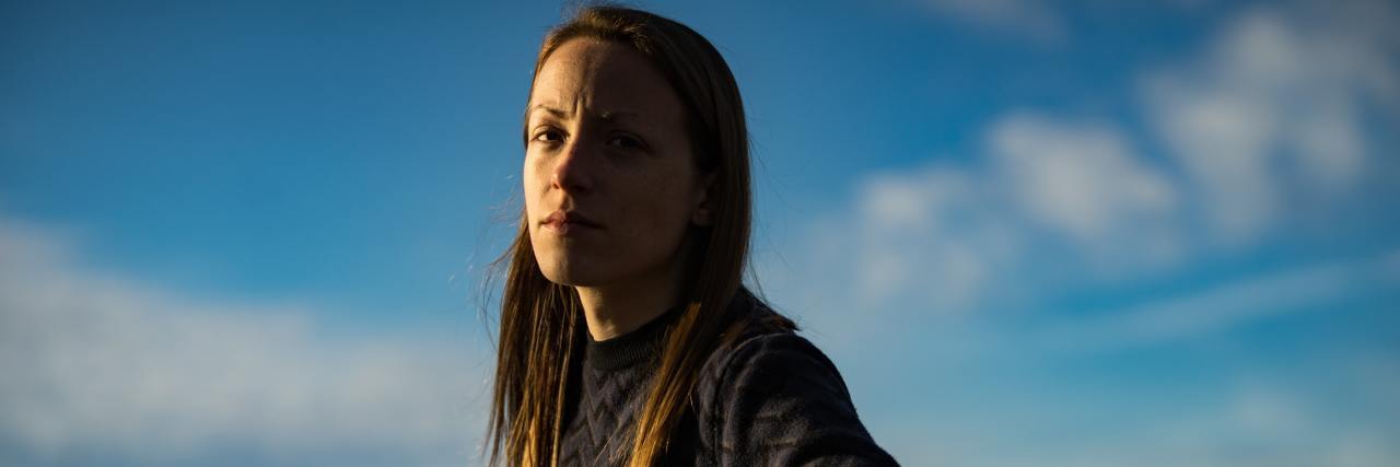 I Had to Change My Suicide Safety Plan Due to COVID-19 Restrictions woman sitting on a park bench turned around with a straight face