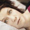 photo of woman lying in bed and staring at camera with wide eyes
