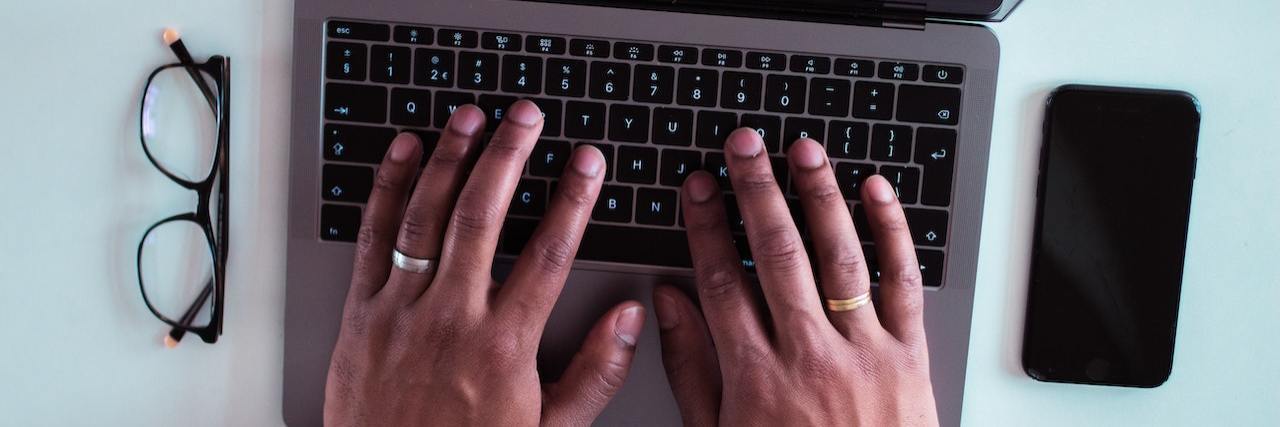 Black man's hands on the keyboard of an open laptop computer