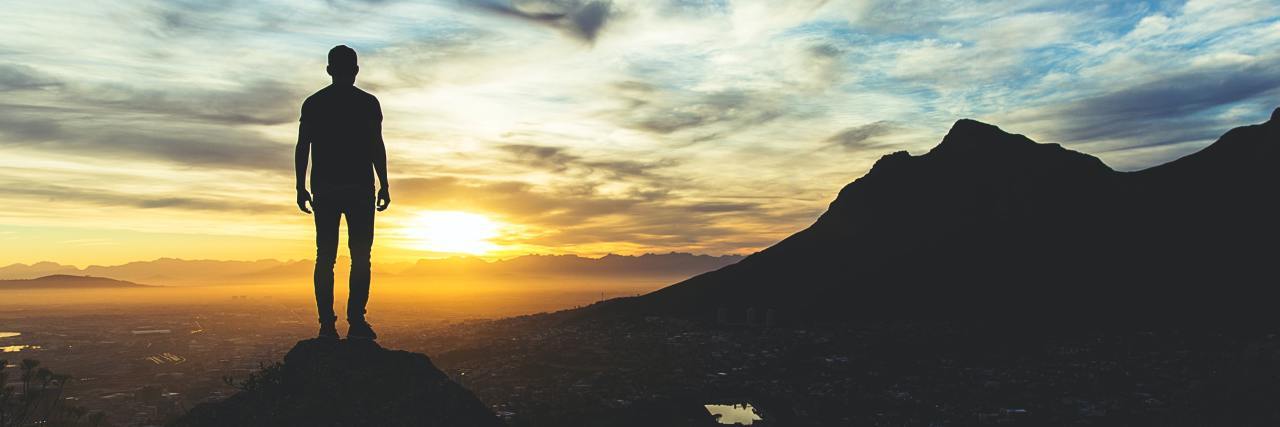 How Borderline Personality Disorder Can Be Seen as a 'Superpower' photo of man standing on mountaintop looking at mountains and sunset in distance