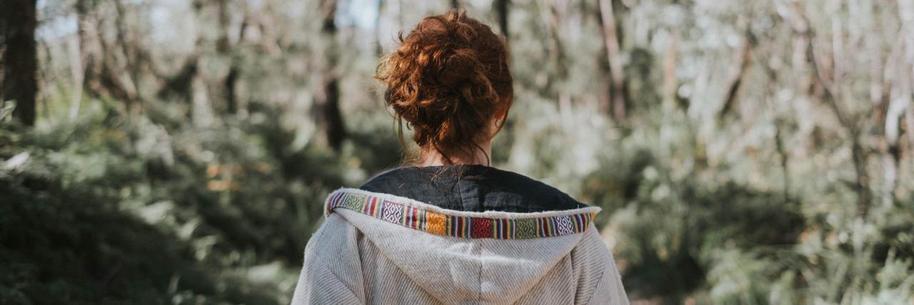 "Yes, and" Thinking Is Helping Me Sit With Depression During COVID-19 back of a woman in a white jacket standing in a forest