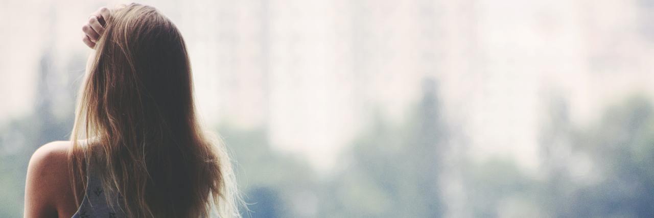 We Need to Talk About Progressive Familial Intrahepatic Cholestasis back of a young woman in a dress staring outside a window