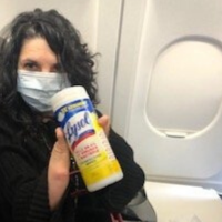 Meg on an airplane holding a container of Lysol wipes.
