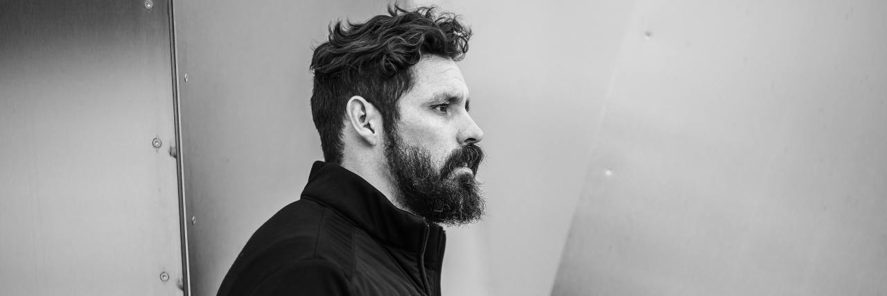 Deciding If Medication for Mental Illness Is the Right Choice for You black and white photo of a man with facial hair standing against a wall