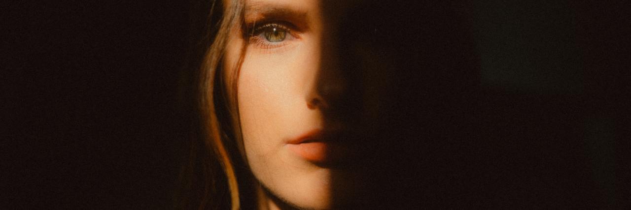 How to Cope With Anxiety Caused by COVID-19 Information photo of woman looking into camera with half of her face hidden in shadow