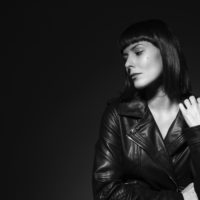 black and white photo of a woman in a leather jacket looking away