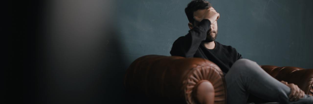 Living With Anxiety and Depression in COVID-19 Self-Isolation A man sitting in a chair, covering his head with his face