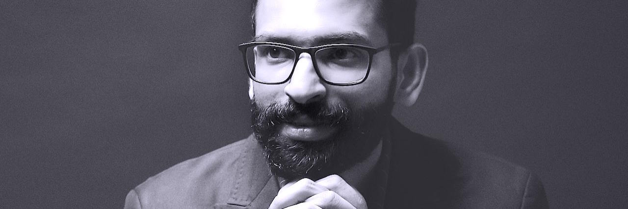 Making Assumptions About People With Invisible Disabilities A black and white portrait of a man with a dark beard and glasses