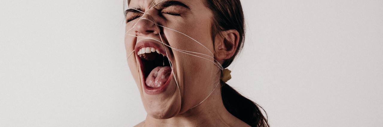 Feeling Like You Can't Scream Because of Childhood Abuse photo of woman screaming with string wrapped around her head