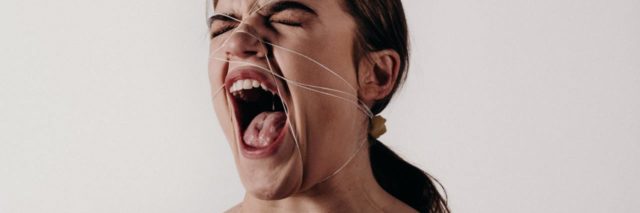 photo of woman screaming with string wrapped around her head