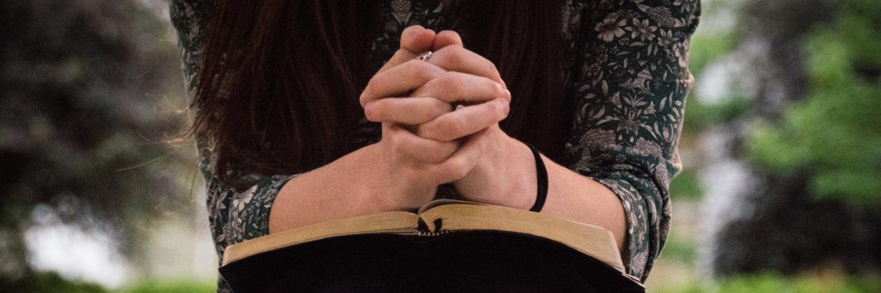 photo of woman with bible on her lap and hands folded