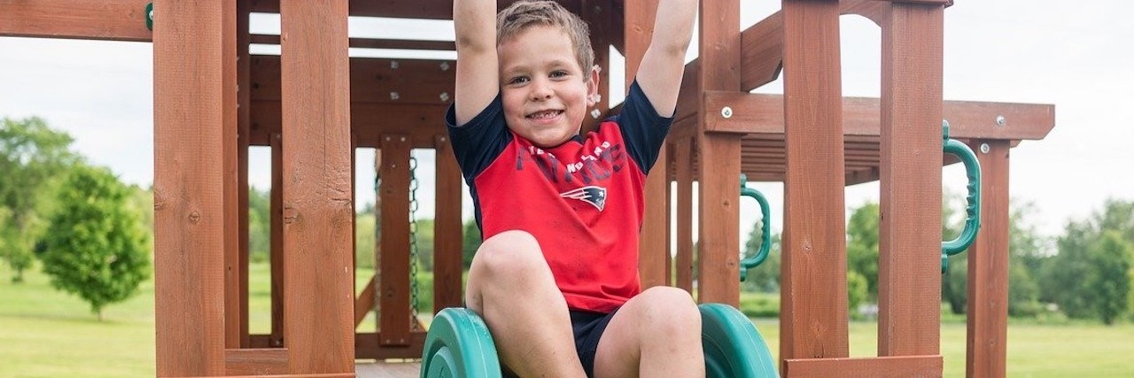 A young boy is sitting on a slide.