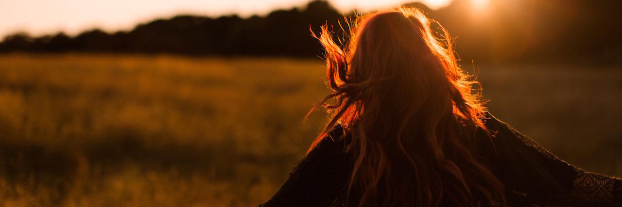 Silhouette of woman in field at sunset