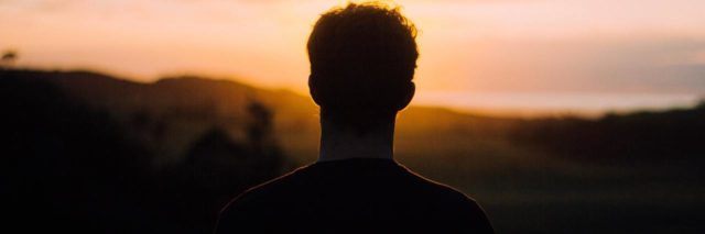 photo of man silhouetted against sunset