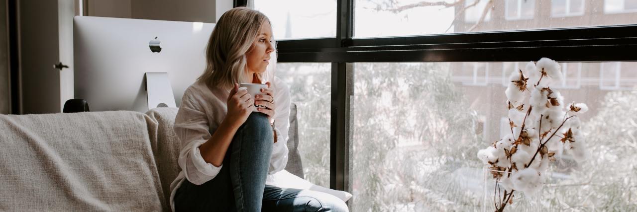 It's OK to Need Alone Time for Your Mental Health During COVID-19 photo of woman sitting alone by window with a mug