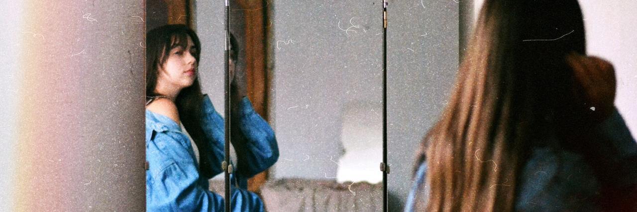 photo of woman looking at herself in mirror