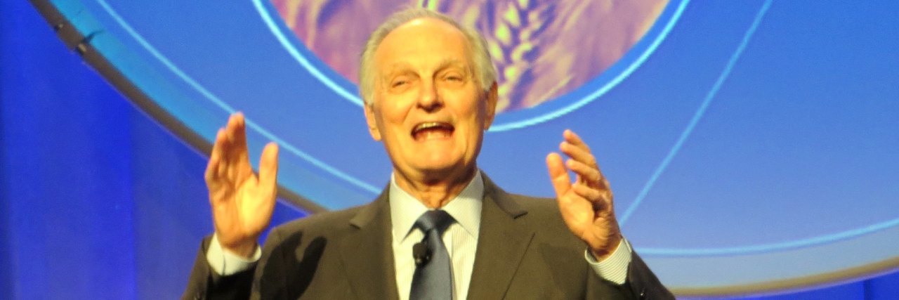 Actor Alan Alda, an older white man with gray hair wearing a dark suit onstage