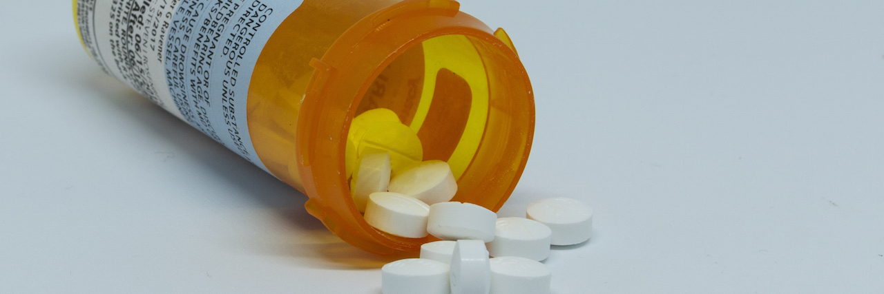 CDC Requesting Stakeholder and Public Comment On Opioids Perscription pain pills are spilling out of the plastic pill container which is laying on its side.