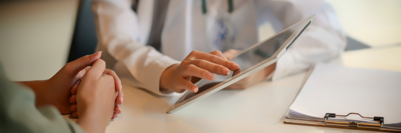 Using Technology to Advocate for Yourself as a Chronic Illness Patient Doctor showing a patient some information on a digital tablet.