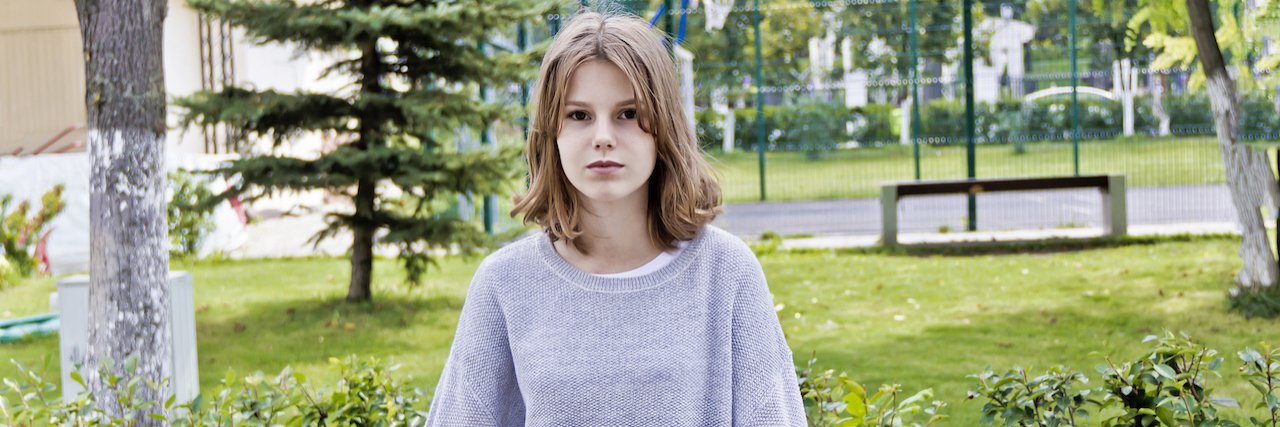 Why I'm Terrified During COVID-19 as a Teenager With Chronic Illness A teenage girl leaning on a bench