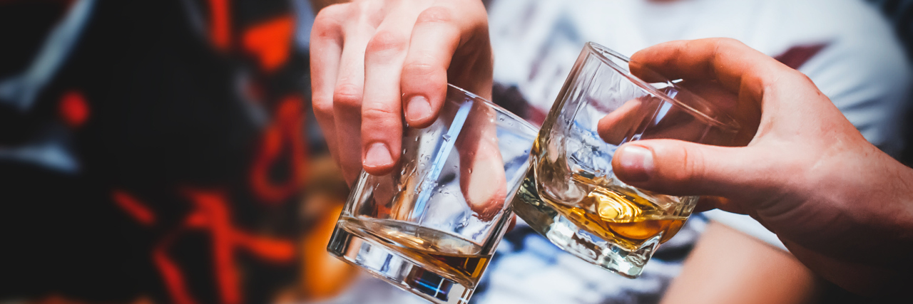 What to Know About Binge Drinking During COVID-19 Two hands clink glasses of whiskey at home,